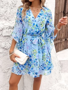 Detail of floral chiffon dress showing V-neckline, tie waist, and ruffled hem in light blue