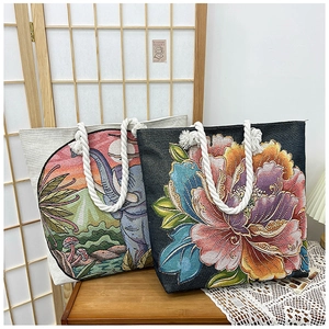 Detail of embroidered elephant sunset and floral patterns on woven tote bag fabric