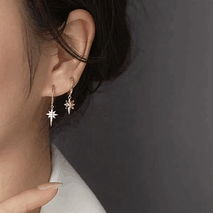 Close-up of elegant rose gold star earrings with zircon stone on a model's ear
