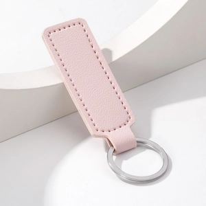 Detail of pink PU leather keychain with silver metal ring and neat stitching on white