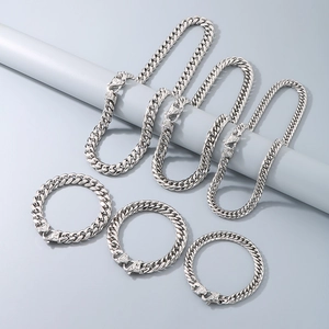 Detailed view of silver Cuban chain necklace and bracelet set with pattern buckles