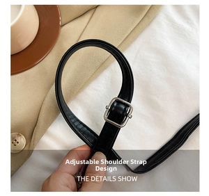 Detail of adjustable black leather shoulder strap with a silver buckle on crescent bag