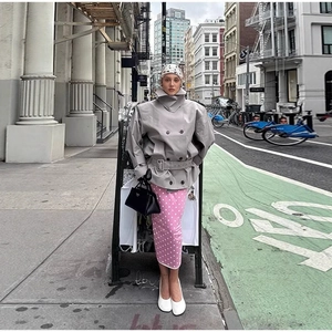 Women's grey high-collar double-breasted trench coat paired with pink polka dot skirt