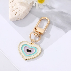 Golden heart keychain with colorful drip oil enamel eye pendant on a textured white stone