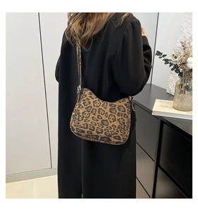 Close-up of a leopard print crossbody bag styled with a professional black coat outfit