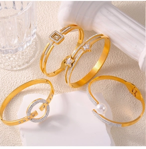 Detail of four gold plated titanium bangles with zircon and pearl accents on stone