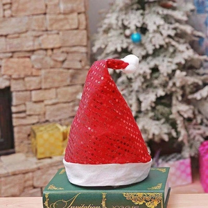 Sparkling red sequin Christmas hat with plush white trim on a green book by a fireplace