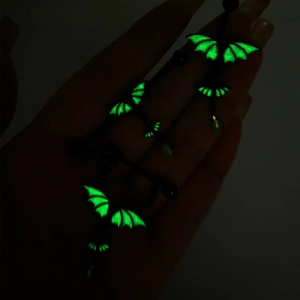 Detailed view of luminous green bat wing jewelry glowing in a dark environment