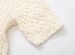 Close-up of cream cable knit sleeve showing thick braided texture and craftsmanship