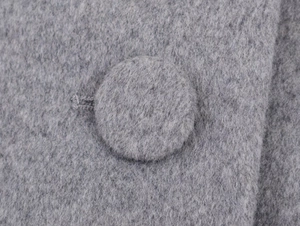 Detail view of grey wool fabric texture with matching large fabric-covered button closure