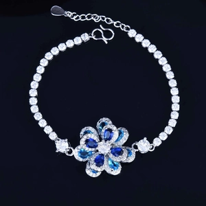 Detail of silver-tone tennis bracelet with blue zircon flower charm and S-clasp