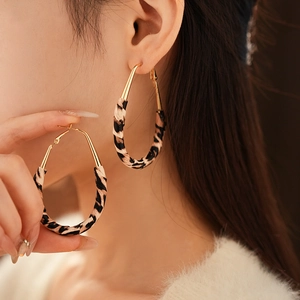 Gros plan de boucles d'oreilles créoles dorées habillées d'un tissu imprimé léopard