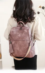 Detail of vintage pink leather backpack featuring stylish tassel and woven strap for women