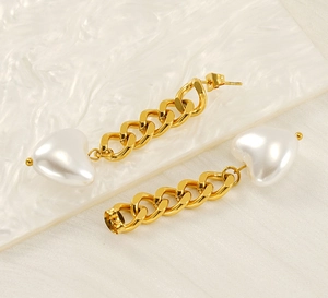 Detail of 18K gold-plated chain earrings with white heart pearl pendants on fabric