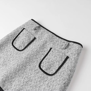 Detailed macro view of black and white tweed skirt with U-shaped pockets and black piping
