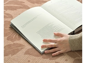 Close-up of a minimalist gold ring worn by a hand holding an open vintage book