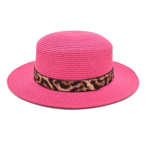 Dettaglio ravvicinato di un cappello di paglia rosa a cima piatta con fascia maculata.