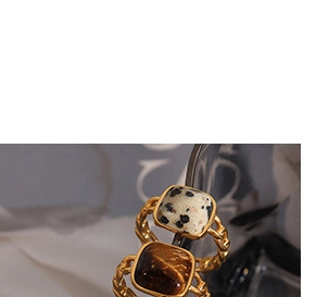 Close-up of vintage gold chain rings featuring Dalmatian stone and tiger eye gemstone