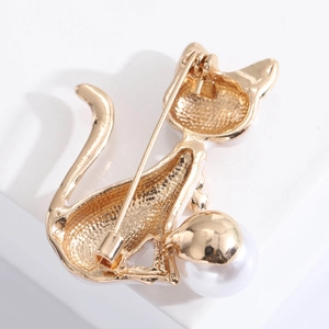Detailed close-up showing the gold cat brooch with pearl accent and the pin mechanism