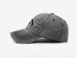Detail of vintage grey washed denim baseball cap featuring distressed holes and scorpion embroidery