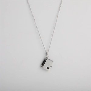 Detailed view of silver book locket pendant with black spine and heart cutout detail