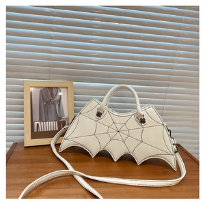 Detailed view of white bat-wing handbag with embroidered spider web pattern and long strap