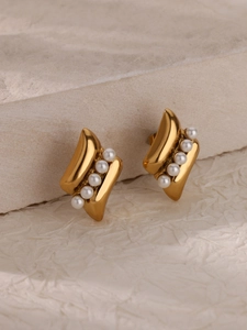 Detail of gold-plated twisted wave earrings featuring five white pearls on a stone