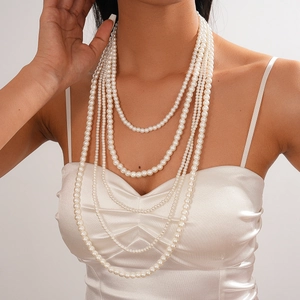Detail of elegant multi-layer pearl necklace on model with white satin top