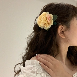 Detailed side view of floral fabric hair claw clip with yellow petals on wavy brown hair