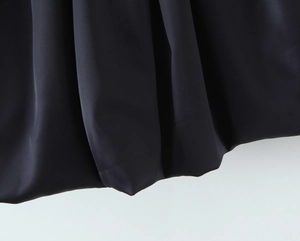 Gros plan détaillé sur la texture en satin noir lisse et l'ourlet de la robe bouffante
