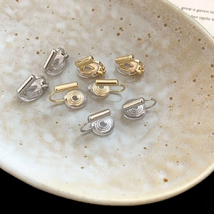 Detailed shot of gold and silver adjustable clip-on earring converters on a ceramic plate