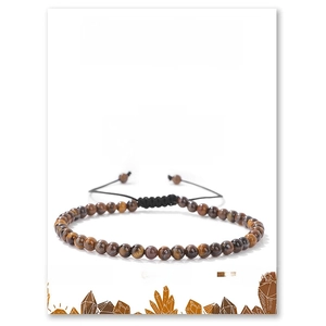 Detailed view of handmade tiger eye beaded bracelet with adjustable black cord on display card