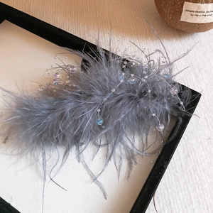 Detailed view of elegant gray feather hair clip with iridescent glass beads in a frame