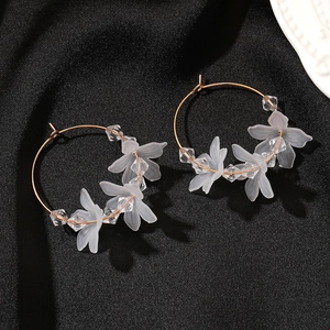 Detail of gold hoop earrings with frosted white petals and clear beads on black silk