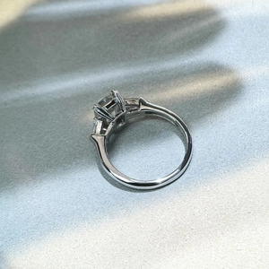 Macro side view of a rectangle-cut moissanite silver ring with a classic three-stone setting