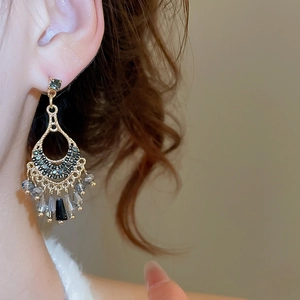 Close-up of vintage tassel earrings with dark rhinestones and grey faceted beads on a model
