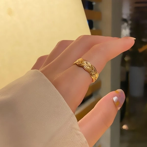 Detailed view of an 18k gold plated titanium steel braided open ring worn on a hand