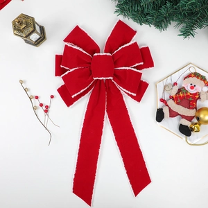 Red velvet Christmas bow with white plush trim on a festive holiday tree branch decor