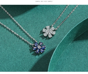 Detailed close-up of a silver flower pendant with blue zircons on a dark green background