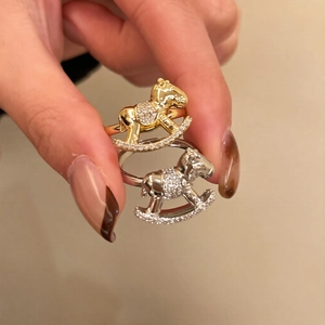 Detailed close-up of golden and silver horse rings with sparkling zircon inlay