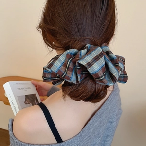 Close-up of a blue and brown plaid fabric scrunchie styled in a woman's hair bun