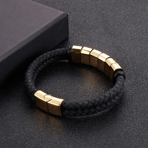 Close-up of black braided leather men's bracelet with gold magnetic metal clasp