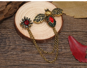 Detailed macro view of vintage bee brooch with red stones and gold tassel chains