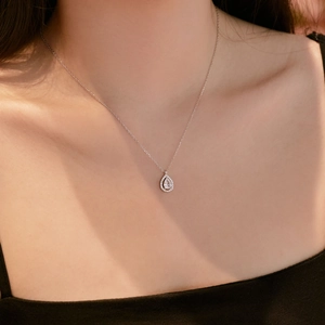 Macro detail of a silver S925 necklace featuring a pear-cut zircon teardrop pendant on model