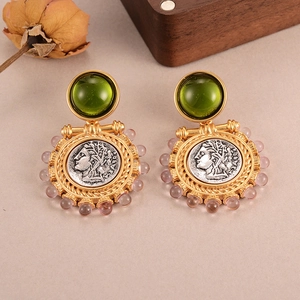 Detailed view of vintage gold earrings with green gemstones and silver coin reliefs