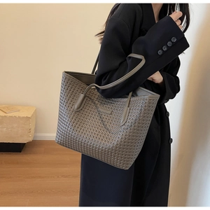 Gray woven texture tote bag held by a model wearing a professional black blazer