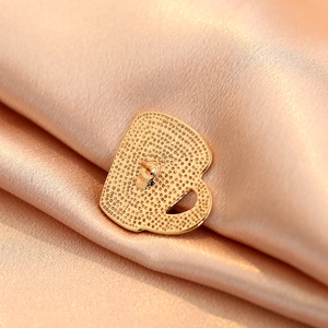 Macro shot of gold alloy coffee cup brooch back with textured pattern and safety pin detail