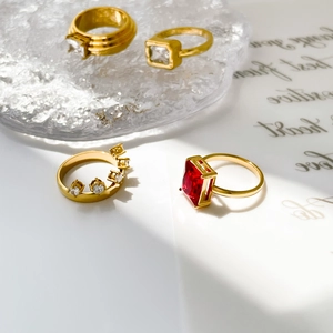Detail showing four gold titanium rings with red and clear cubic zirconia on ice cubes