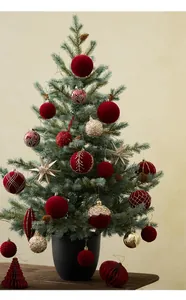 Detailed view of red flocked balls and gold ornaments on a mini desktop Christmas tree