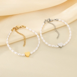 Elegant gold and silver heart pendant pearl bracelets with oval beads on silk background